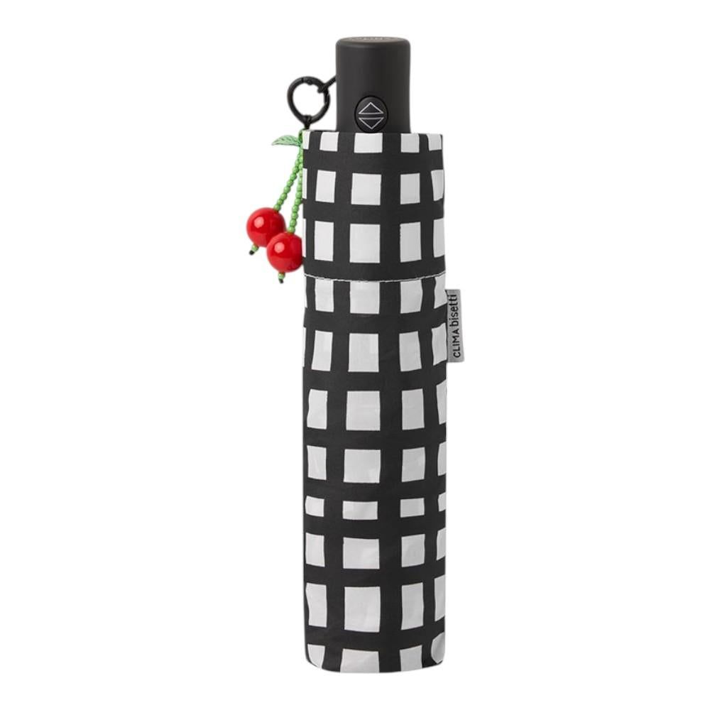 Vista frontal del paraguas plegable Bisetti Gridix negro con estampado geométrico, protección UV50+ y colgante decorativo de cerezas.