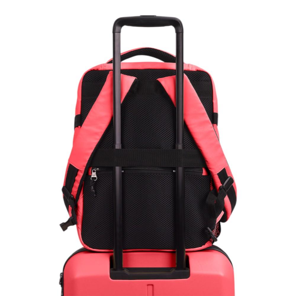 Mochila de viaje Luisipo Gabol Vancouver color coral acoplada al asa de una maleta trolley mediante su cinta trasera.